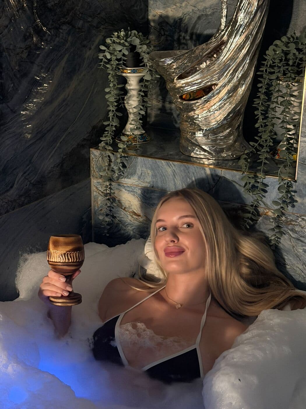 Guest relaxing on a hammam bench surrounded by candles