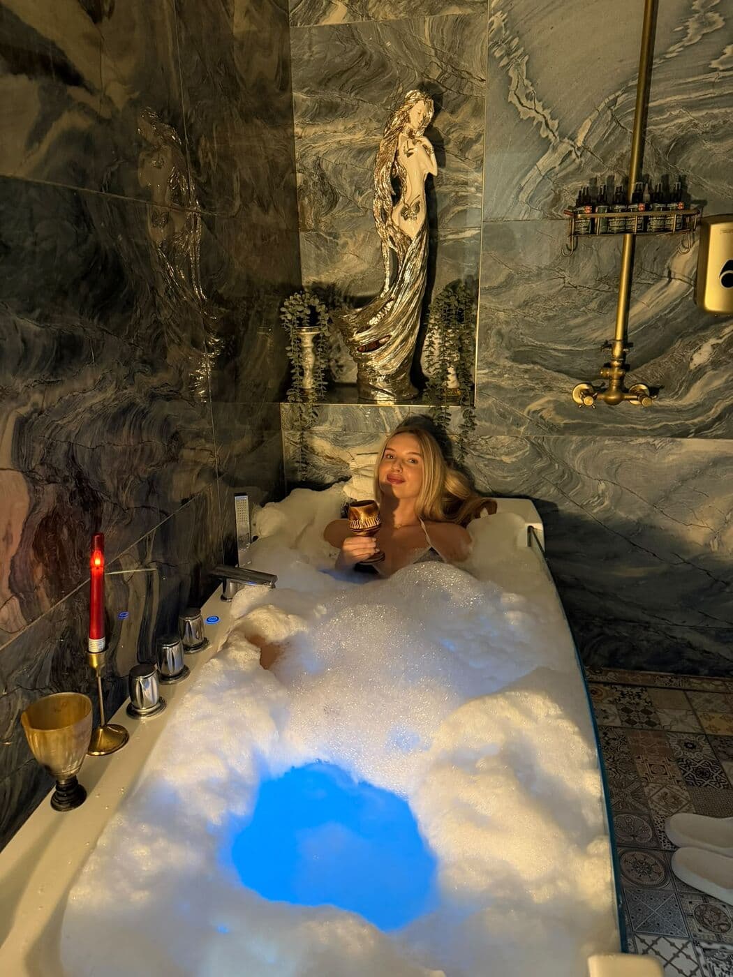 Guest covered in foam on a hammam table under blue light